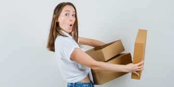 Beautiful lady in white blouse holding boxes and looking surprised , front view.
